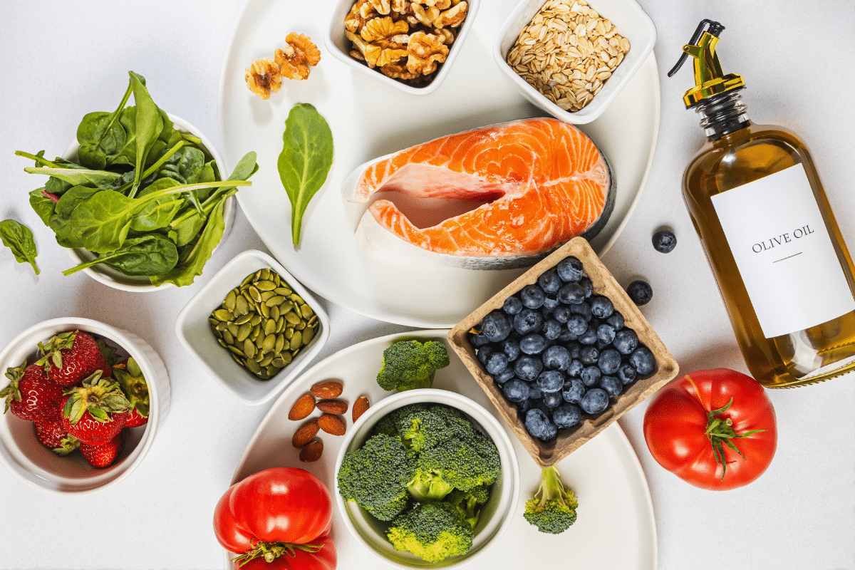 A variety of fruits and vegetables including broccoli, tomatos, spinach, and strawberries, and seeds 